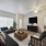 Garden-Style Apartments in Flagstaff, AZ, with In-Unit Washer and Dryer - Sterling Pointe - Living Room with Wood-Style Flooring, L-Shaped Couch, Armchair, Ottoman Served as Coffee Table, Media Cabinet, and Mounted TV.