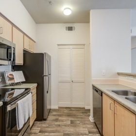 Garden-Style Apartments Near Target - Sterling Pointe - Kitchen with Wood-Style Flooring, Customized Cabinetry, Countertops, Range, Microwave, Dishwasher, and Refrigerator.